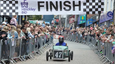 Driver in crash helmet in soap box car 