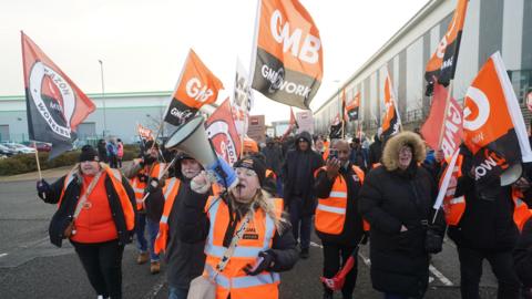 Members of the GMB union on the picket line stand in front of a freight lorry outside the Amazon fulfilment centre in Coventry