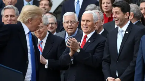 Getty Images U.S. President Donald Trump (L) jokes with Senate Majority Leader Mitch McConnell (R-KY), Sen. Mike Enzi (R-WY), Vice President Mike Pence, Spaker of the House Paul Ryan (R-WI) and Sen. Tim Scott (R-SC) during an event celebrating the passage of the Tax Cuts and Jobs Act on the South Lawn of the White House December 20, 2017 in Washington, DC.