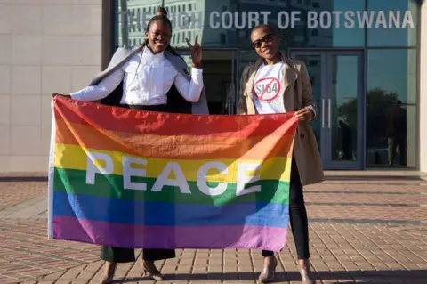 AFP Two activists pose with a rainbow flag as they celebrate outside Botswana High Court in Gaborone on 11 June.