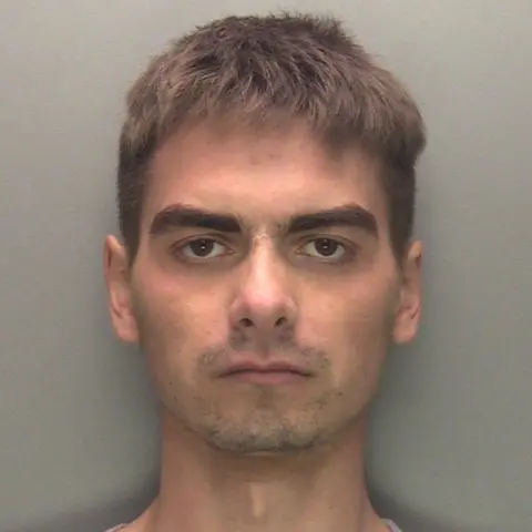 Lincolnshire Police A police custody photograph of a man with short brown hair frowning as he looks into the camera with a serious expression. He is wearing a grey top and a grey wall is behind him.