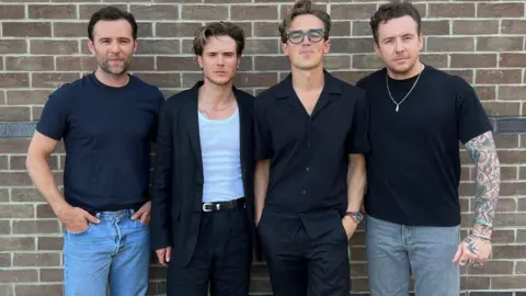 McFly standing in front of a brick wall