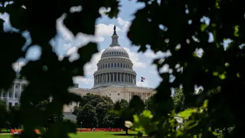Getty Images View of Capitol building, a large white building through green trees