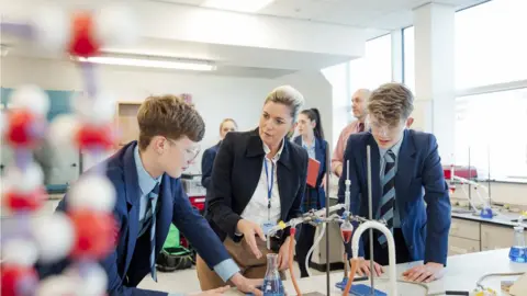 Getty Images A teacher talks to pupils in a science lab