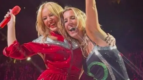 Kylie Minogue on stage with fan Faye Louise smiling at O2 in London.