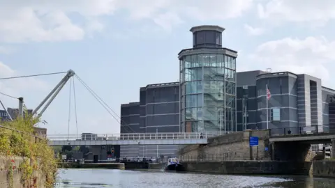 Getty Images Royal Armouries in Leeds, a large modern building built adjacent to the river with a pedestrian bridge across the water