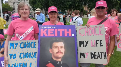 Keith's family hold placards outside Parliament