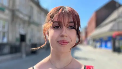 Teenage girl with tied back died red hair.