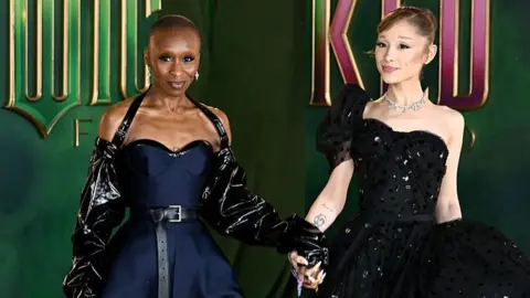 Getty Images Cynthia Erivo and Ariana Grande are pictured holding hands and smiling at each other as they arrived for the European premiere in London of Wicked: For Good.