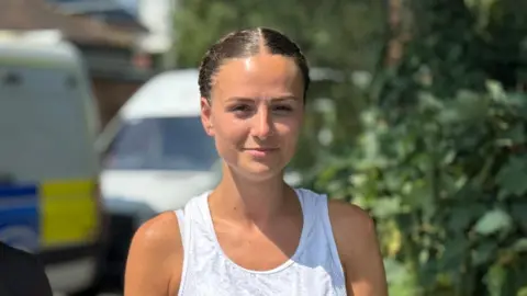 Sgt Kate Clarke pictured with her brown hair tied back and wearing a white sports vest.