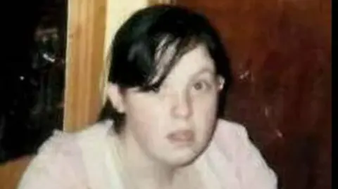 Handout An image of Elizabeth Clarke who has short black hair tied up in a ponytail with a side fringe. She is wearing a pink top and has brown eyes. 