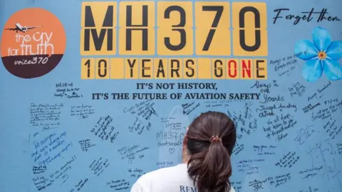 EPA Seorang anggota keluarga penumpang dan kru di atas pesawat Malaysia Airlines yang hilang MH370 Tulis di dinding peringatan selama acara peringatan menandai peringatan 10 tahun hilangnya Kekaisaran di Subang di Subang Jaya, Selangor, Malaysia, 03 Maret 2024