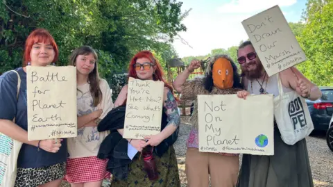Five protesters hold placards outside Keswick Reading Room during the consultation.