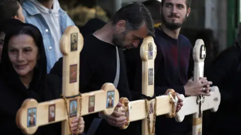 EPA A Christian Orthodox pilgrim leans his head on a cross during a Good Friday procession