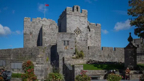 MANX SCENES Castle Rushen, which had a square tower with a clock face on it and a Manx flag flying from the ramparts.