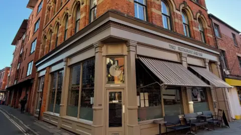 TNQ The exterior of the TNQ building. Beige panelled exterior with brown striped sun shades.