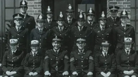 Thames Valley Police A three rows of police officers, the image is in black and white.
All the officers are wearing uniform, with four women sat in the front row. They are all looking at the camera.