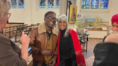 Jon Wright/BBC A man poses for a photography with a women. They are inside a cathedral and are smiling.