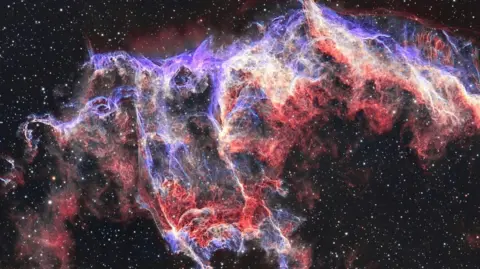 Lee Pullen/UrbanAstrophotography.com The Bat Nebula is a glowing bright purple and red collection of gasses that loosely form the shape of a bat. 