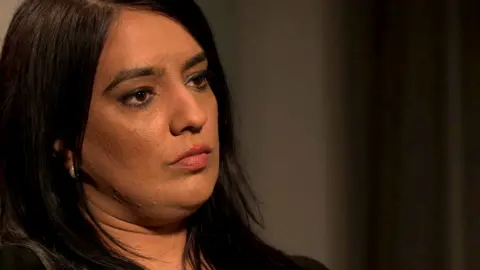 A woman with dark hair and silver earrings