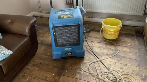 BBC Bare damp floorboards at home of Loughborough council tenant.