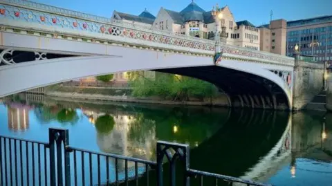 A grand white bridge over the River Ouse, with red trim. Some rust is visible.
