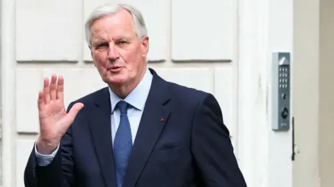 THOMAS SAMSON/AFP Perdana Menteri yang baru dilantik Michel Barnier memberi isyarat sebelum upacara serah terima jabatan di Hotel Matignon di Paris, pada 5 September 2024