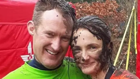 Contributed Mr and Mrs Putwain smile at the camera while standing closely together. They are covered in mud following a mud race.