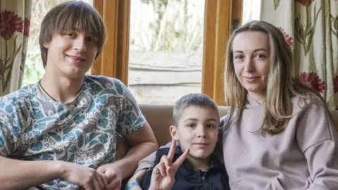 Ukrainian refugees Yaroslav Kryvoshyia (left) and Irina Kryvoviaz (right) with her son Sasha as they settle into their new home in North Moreton