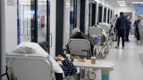 BBC A line of beds in a hospital corridor