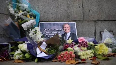 Reuters Floral tributes to Sir David Amess left outside Parliament