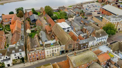 West Norfolk Borough Council Aerial view of St George's Guildhall complex. The front of the building contains the theatre. Alongside is an internal courtyard flanked by two large barns leading to the river.