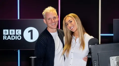 Jamie Laing and Sophie Habboo smiling together in the Radio 1 studio