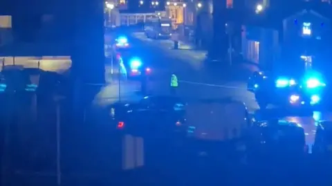 Police outside Chester railway station. A cordon is in place blocking the road and an officer in a hi-vis jacket stands in front of the tape. 