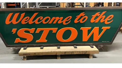 Museum of London Orange lettering on a green sign that reads "Welcome to the 'Stow"