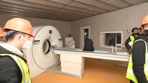 EPA Workers set up a CT scanner inside the hospital