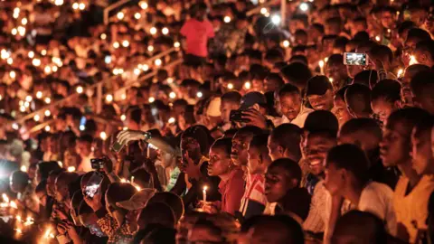 AFP People hold candles as they attend a night vigil and prayer at the Amahoro Stadium as part of the 25th commemoration of the 1994 genocide in Kigali, Rwanda - Sunday 7 April 2019