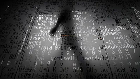 AFP File photo showing a person walking behind a glass wall bearing machine coding symbols (17 October 2016)