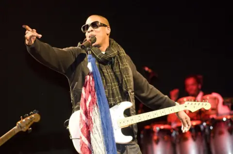 Hayley Madden / Getty Images Jay-Z points to the crowd while holding a guitar