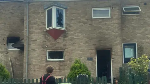 Supplied The outside of a house. The windows are blown out and the front door is open with signs of smoke damage.