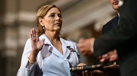 Darline Graham is sworn in to the Senate. Her right hand is raised, under oath.