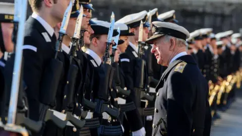 Chris Jackson/Getty Dressed in naval uniform King Charles III, the Lord High Admiral, inspects the Guard who are holding bayonets