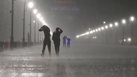 People seen covering their heads during heavy rainfall and a storm at Kartavyapath on May 21, 2025 in New Delhi, India.