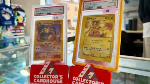 Danny Fullbrook/BBC Two Pokemon Cards berdiri tegak di atas meja dalam tampilan bermerek cardhouse kolektor. Salah satunya adalah kartu charizard gelap, yang lainnya adalah kartu Pikachu dengan teks Jepang. 