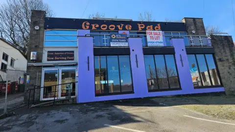 Front of pub called Groove Pad, with black and orange branding and purple frontage. 'To Let' signs indicate it is closed.