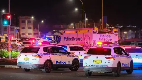 Getty Images A sea of flashing red and blue lights, along with police vehicles, can be seen on a packed roadway.