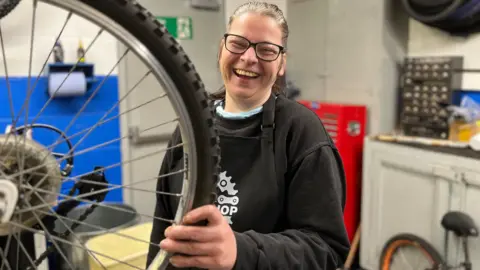 A woman  working on a bicycle in a repair shop 