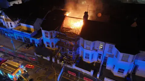 Eddie Mitchell Night time aerial photo of firefighters tackling a blaze in a row of terraced properties.