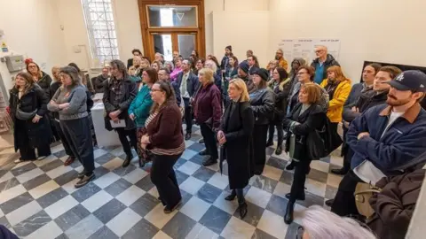 Blackpool Council Scores of people stand in a Grundy Art Gallery room as they listen to a speech. 