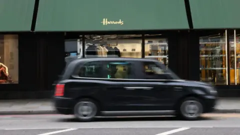 PA Media File image showing a black cab driving past Harrods department store in central London